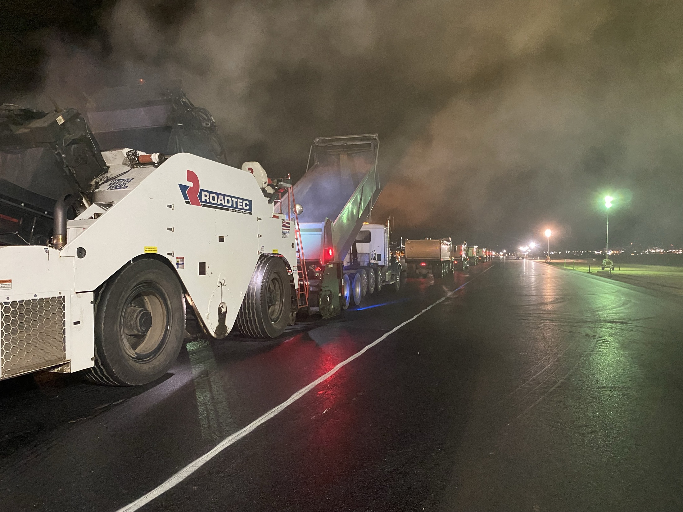 Night paving equipment and trucks working under runway lights